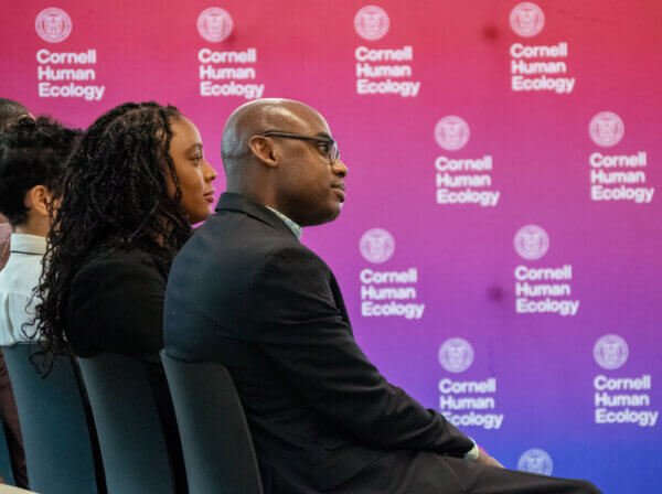 Man and women sit watching a panel discussion