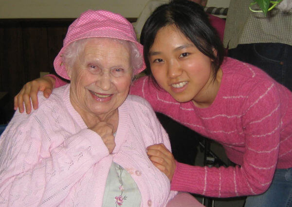 older woman in a pink hat poses with young woman